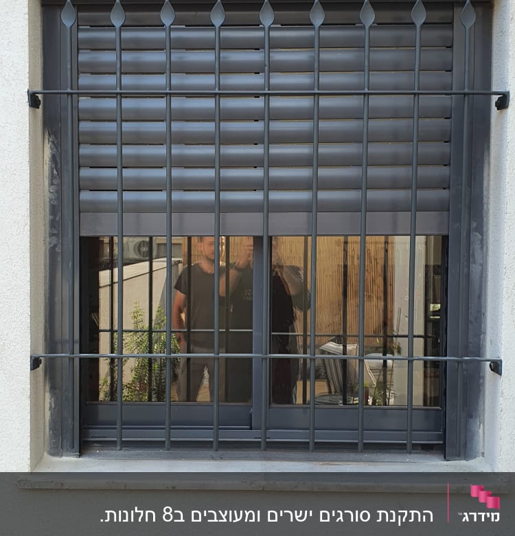 סורגי מתכת על חלון עם תריסים סגורים